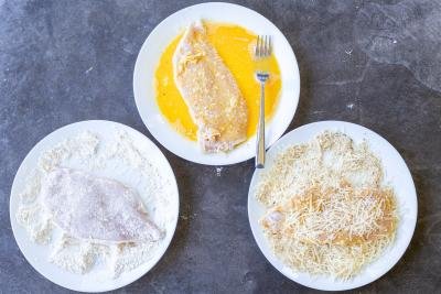 Seasoned and coated chicken on different plates.