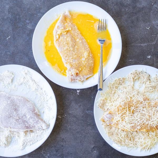 Seasoned and coated chicken on different plates.