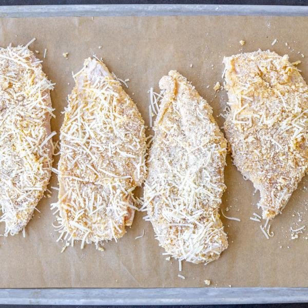 Coated chicken breast on a baking sheet.