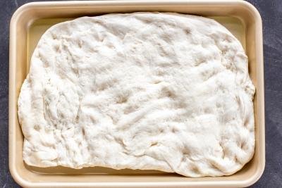 Focaccia dough on a baking pan.