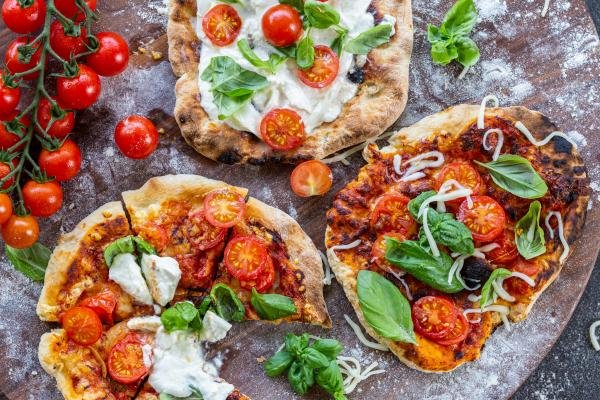 Sliced pizzas with different toppings on a tray.