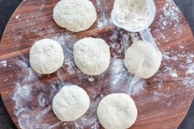 Divided pizza dough on trays with flour.