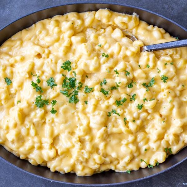 Mac and cheese in a pan with herbs on top.