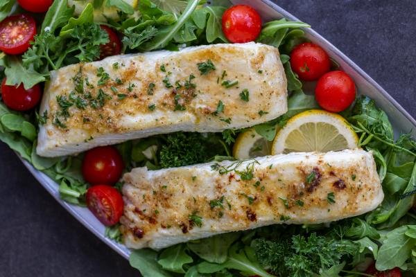 Baked Halibut on a plate with herbs and greens.