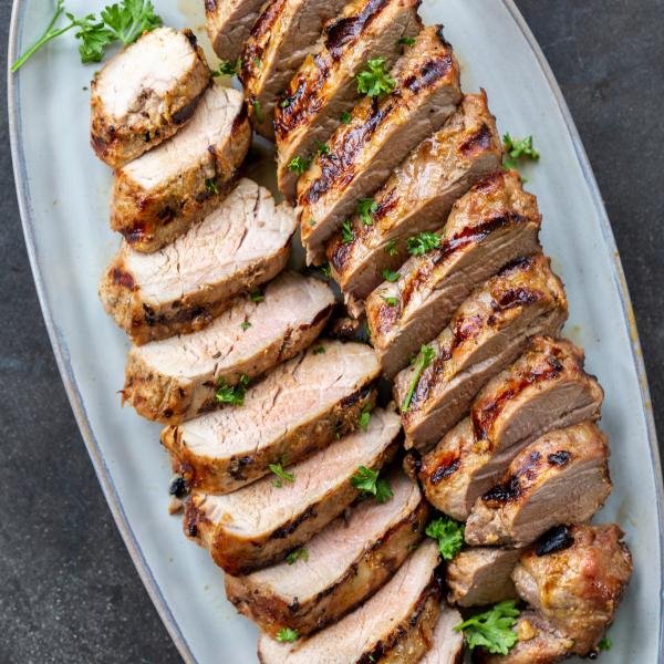 Grilled pork tenderloin sliced up on a plate.