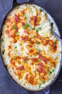 Baked Scalloped Potatoes in pan with a spoon.