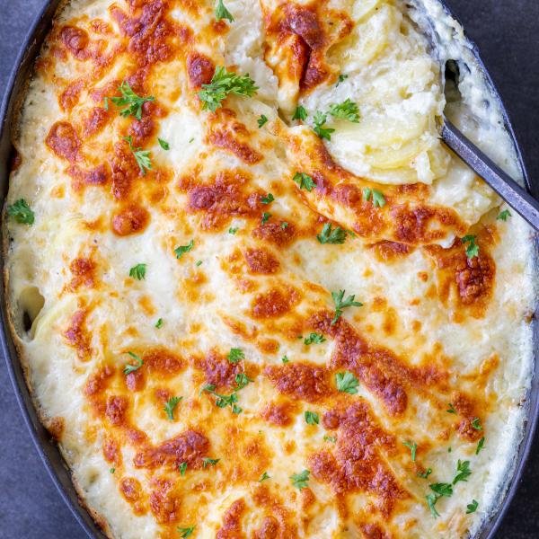 Baked Scalloped Potatoes in pan with a spoon.