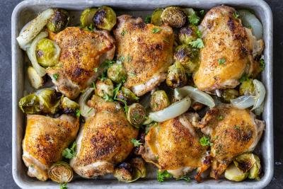 Baked Sheet Pan Chicken Thighs with Veggies with herbs on a pan.