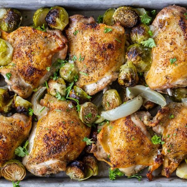 Baked Sheet Pan Chicken Thighs with Veggies with herbs on a pan.