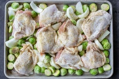 Seasoned chicken with veggies on a pan.