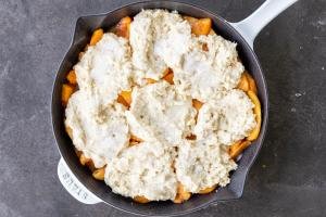 Peaches with cobbler topping in a pan.