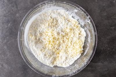 Butter added to the dry ingredients in a bowl.