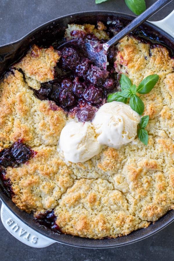 Cherry Cobbler topped with ice cream and a spoon in. 