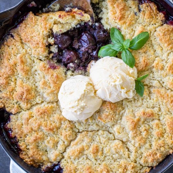 Cherry Cobbler in a baking pan served with ice cream.