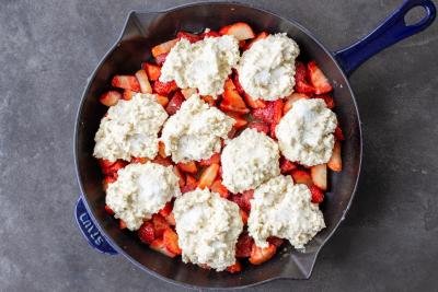 Strawberries in a pan with cobbler dough on top.
