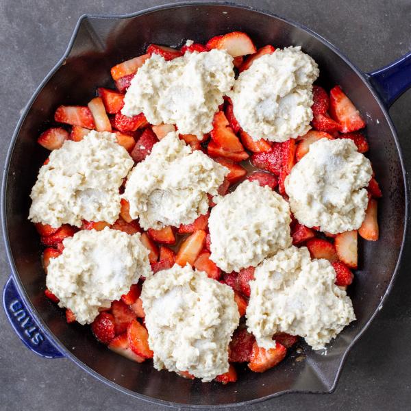 Strawberries in a pan with cobbler dough on top.
