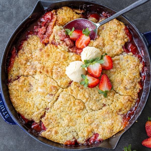 Strawberry Cobbler in a pan with berries and ice cream