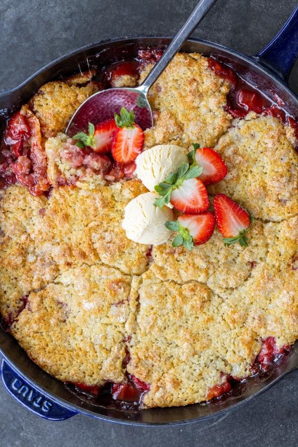 Strawberry Cobbler in a pan with ice cream and strawberries. 