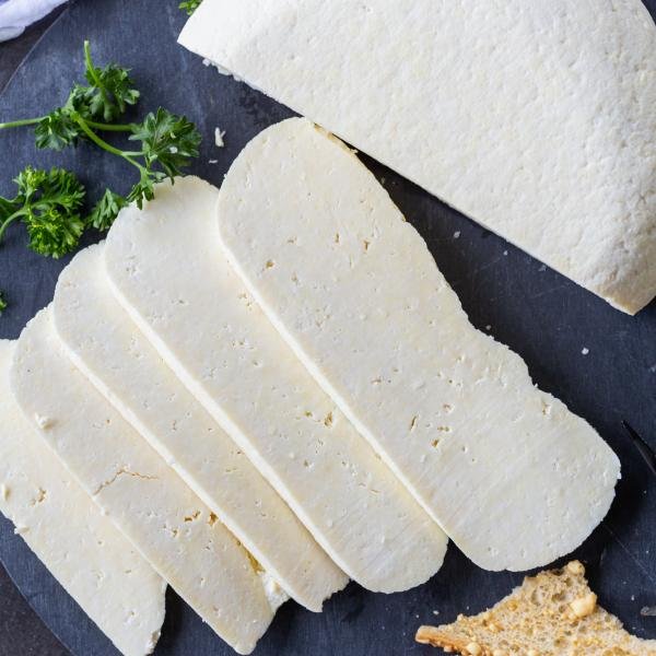 Sliced homemade cheese on a tray with crackers.