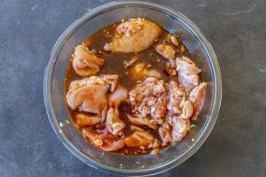 Chicken marinading in a bowl with sauce.