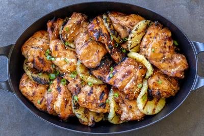 Grilled Huli Huli chicken on a serving tray with pineapple.