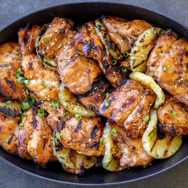 Grilled Huli Huli chicken on a serving tray with pineapple.