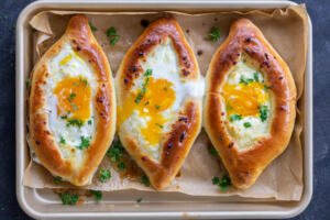 Baked Khachapuri on a baking with herbs.