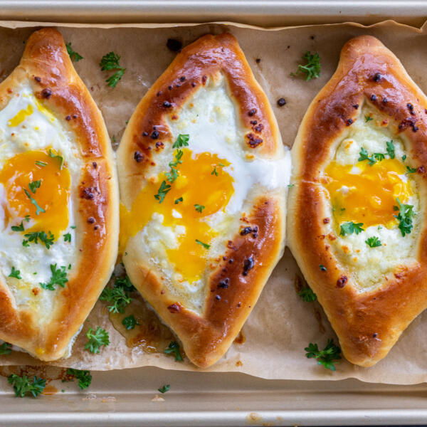 Baked Khachapuri on a baking with herbs.