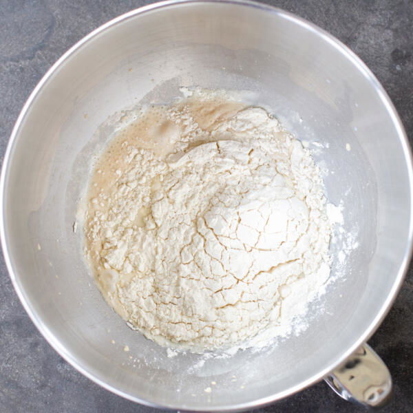 Flour added in a mixing bowl with liquids.