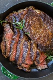 Ribeye with rosemary in a pan.