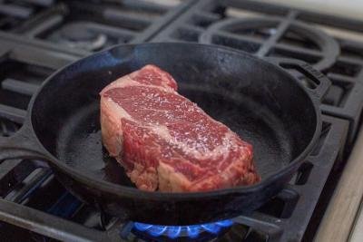 Ribeye cooking on a cast iron.