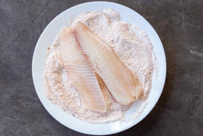 Tilapia coating in a seasoning on a plate.