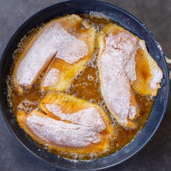 Tilapia frying in a pan.
