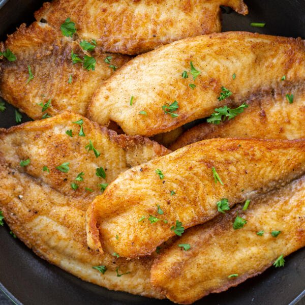 Pan Fried Tilapia on a pan with herbs.