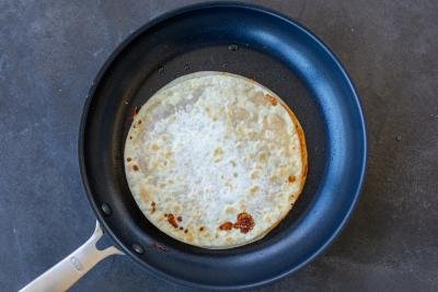 Cooking quesadilla on a frying pan.