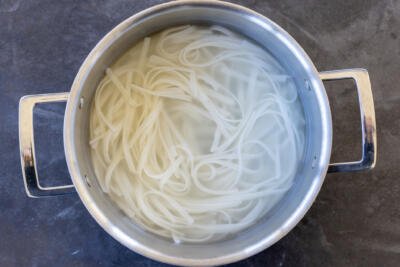 Rice noodles cooking in a pot.