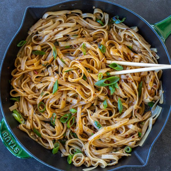 Spicy noodles in a pan with chop sticks.