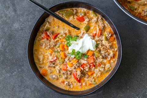 Stuffed Peppers Soup in a bowl with a spoon and topped with sour cream.