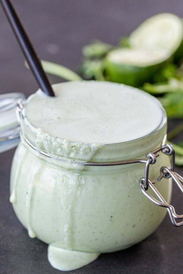 Creamy Tomatillo Dressing with a spoon in a jar.