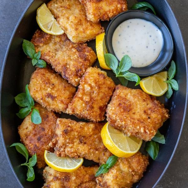 Crispy Panko Fish on a serving tray with lemon wedges.