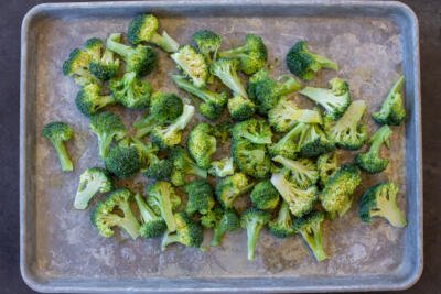 Seasoned broccoli on a baking sheet.