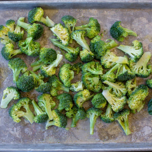 Seasoned broccoli on a baking sheet.