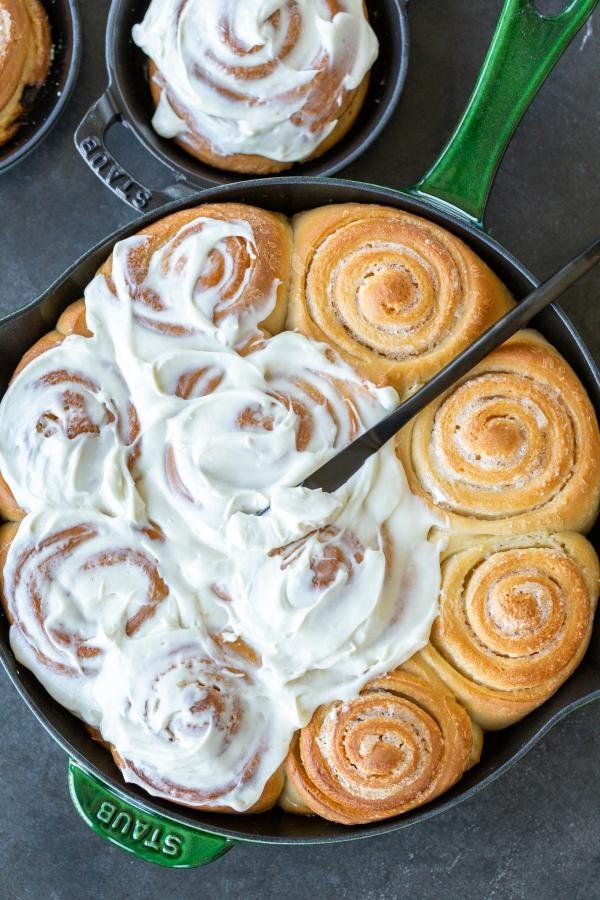 Cream cheese frosting on top of cinnamon rolls.
