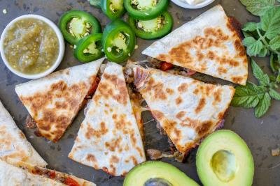 Steak Quesadilla on a tray with toppings.