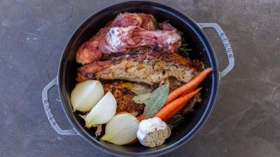 Bones and veggies in a pot and herbs.