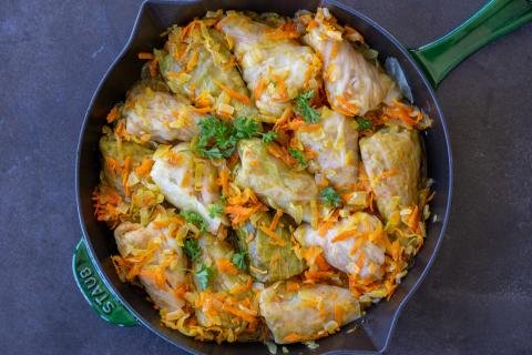 Vegetarian cabbage rolls in a pan with veggies and herbs.
