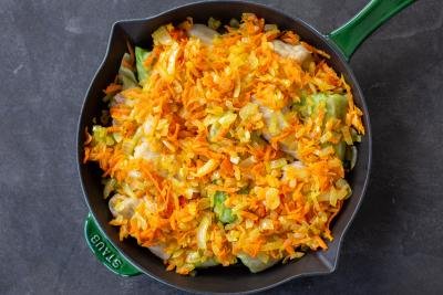 Cabbage rolls covered with veggies in a pan.