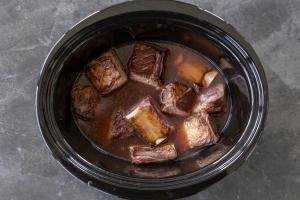Broth with beef short ribs in a slow cooker.