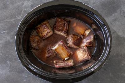 Broth with beef short ribs in a slow cooker.