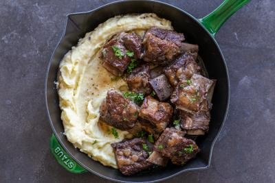 Slow cooker short ribs in a pan with herbs.